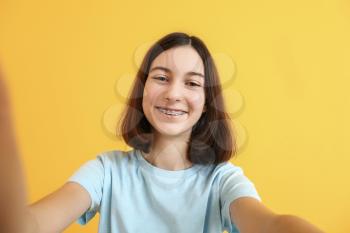 Teenage girl with dental braces on color background�