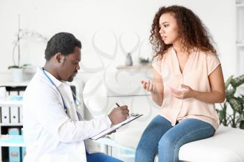 Male African-American doctor examining patient in clinic�