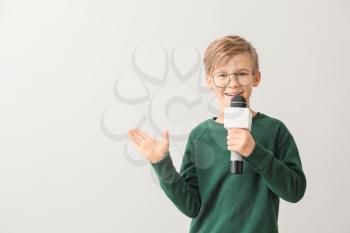 Little journalist with microphone on white background�