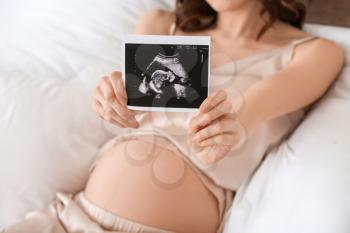 Beautiful pregnant woman with sonogram image at home�