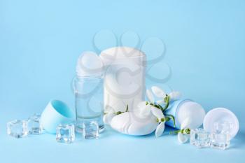 Different deodorants and flowers on color background�