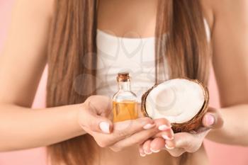 Young woman with coconut oil for hair on color background, closeup�