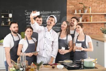 Male chef and group of young people taking selfie during cooking classes�