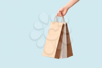 Female hand with paper shopping bags on color background�