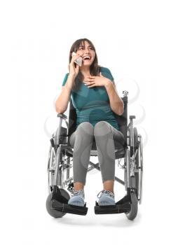 Young woman in wheelchair talking by mobile phone on white background�