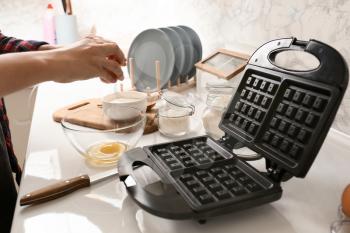 Woman making dough for waffles in kitchen�