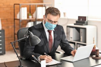Male lawyer in protective mask working in office�