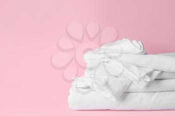Stack of clean bed sheets on color background�