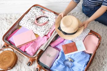 Woman packing suitcase for journey at home�
