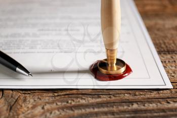 Document with notary public wax seal on table, closeup�