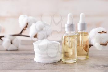 Bottles of cottonseed oil with cosmetic pads on table�
