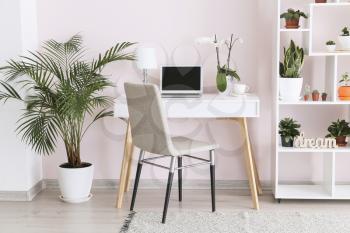 Stylish interior of room with green houseplants and workplace�