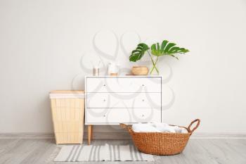 Baskets with towels and chest of drawers with cosmetics in bathroom�