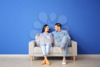 Young couple with laptop relaxing on sofa at home�