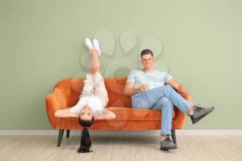 Young couple relaxing on sofa near color wall�
