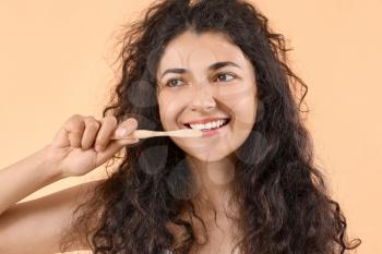 Beautiful young woman with wooden toothbrush on color background�