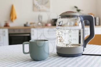 Electric kettle and cup on kitchen table�