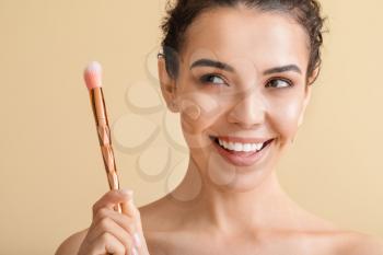 Beautiful young woman with foundation on her face against color background�