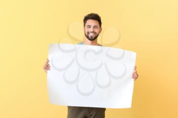 Young man with blank paper sheet on color background�