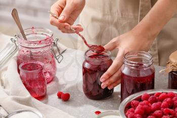 Woman with jars of sweet raspberry jam�