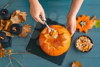 Woman carving pumpkin for Halloween at table�