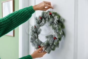 Woman hanging beautiful Christmas wreath on door�