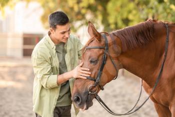 Young man with cute horse outdoors�
