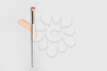 Sample of makeup foundation and brush on light background�