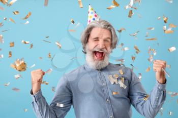 Mature man celebrating birthday on color background�