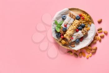 Plate with healthy cereal bars, berries and nuts on color background�