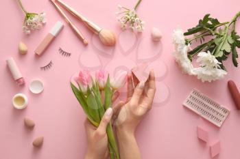 Hands with flowers and cosmetics on color background�