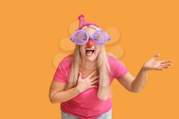 Mature woman in funny disguise on color background. April Fools Day celebration�