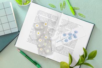 Book with bookmarks and stationery on color background�