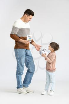 Little boy greeting his dad on Father's Day against light background�