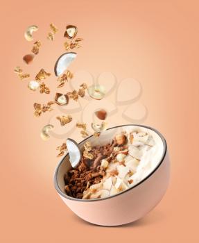 Tasty granola with yogurt and nuts in bowl on color background�