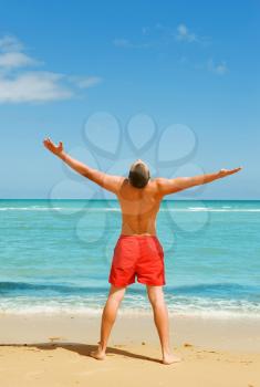 man standing on the beach spreading his hands