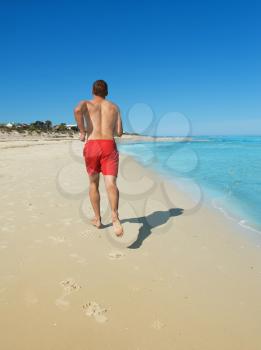 muscular young man running along the coast