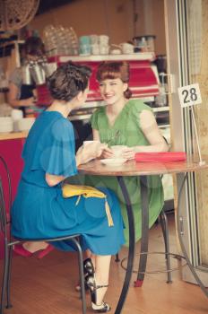 Two beautiful girls in retro style in retro cafe
