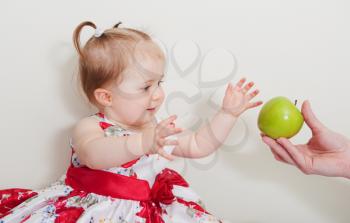 beautiful baby girl with green apple on a light background