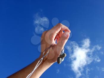 Royalty Free Photo of a Hand Holding Earbuds Against the Sky
