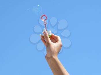 Royalty Free Photo of a Woman's Hand Holding a Bubble Wand to the Sky