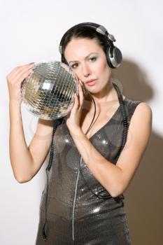 Portrait of beautiful young woman in headphones with a mirror ball