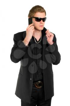 Young man in sunglasses wearing black clothes and talking on the mobile phone. Isolated