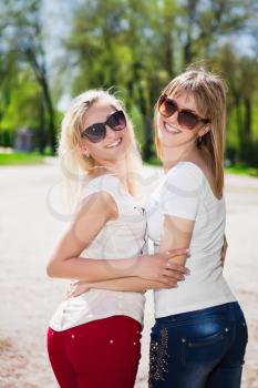 Two playful women wearing sunglasses and white t-shirts