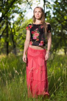 Thoughtful blond woman posing in red skirt and flowering blouse