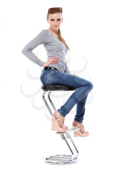 Pretty blond woman in casual clothes posing at the bar chair. Isolated on white