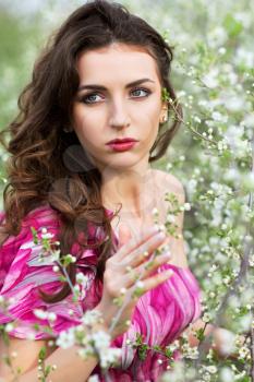 Portrait of thoughtful nice brunette posing in flowering trees