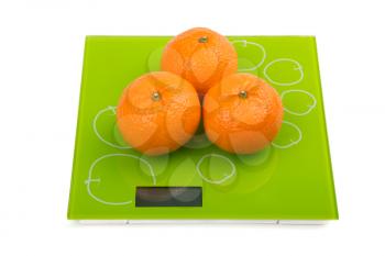 Close-up of three sweet mandarin on scales. Isolated