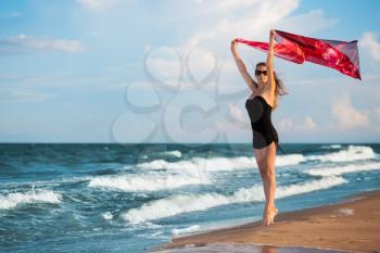Attractive leggy woman with pink pareo posing near the sea