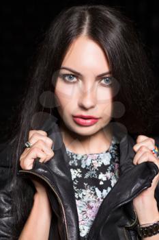 Portrait of young attractive woman posing in black leather jacket. Isolated